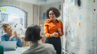 A presenter standing in front of seated employees: HR manager presenting benefit options at an employee open enrollment meeting