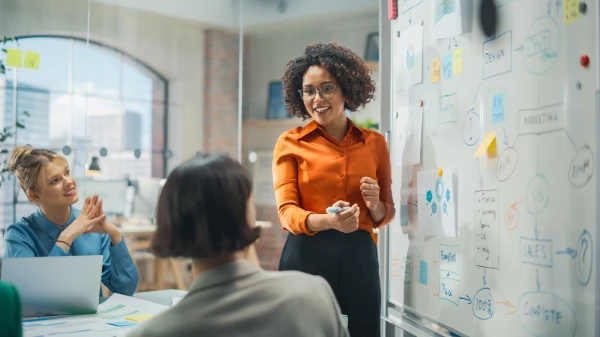 A presenter standing in front of seated employees: HR manager presenting benefit options at an employee open enrollment meeting